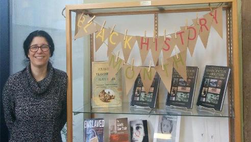 Librarian Beth Clinton stands next to a display for Black History Month