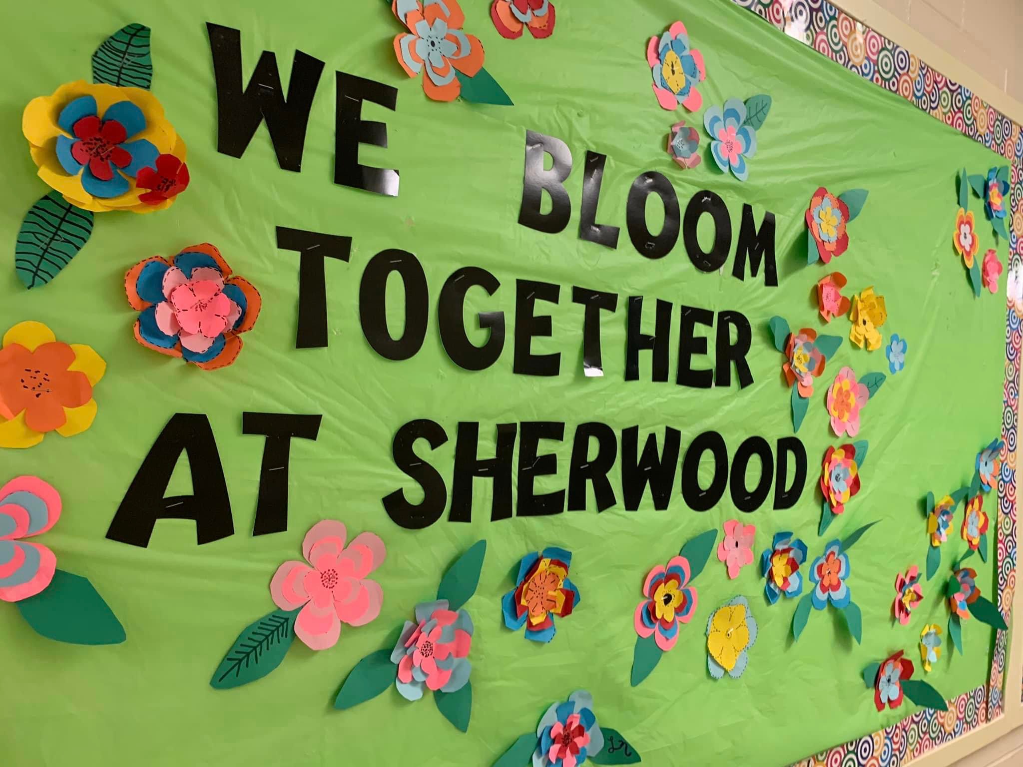 image of a green poster on a wall with paper flowers and words on it