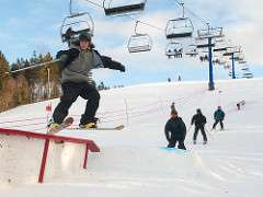 Young guy hits a snowboard jump at Brookvale Ski Park