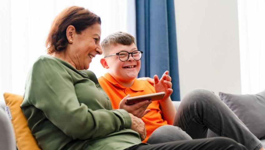 image of an older person and a younger person sitting on a couch and laughing