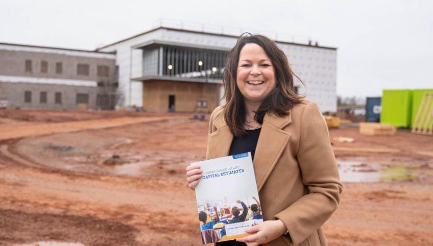 image of a person holding a document while standing in front of a building under contruction