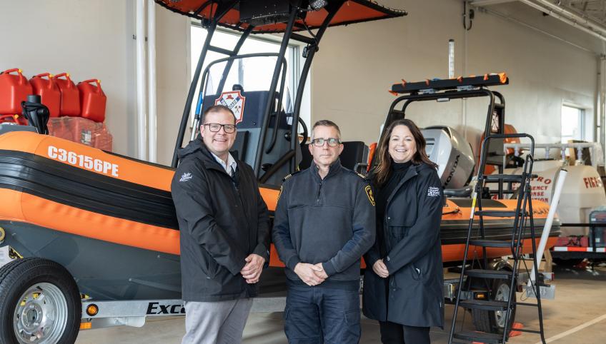 image of three people in front of a small rescue boat inside a garage