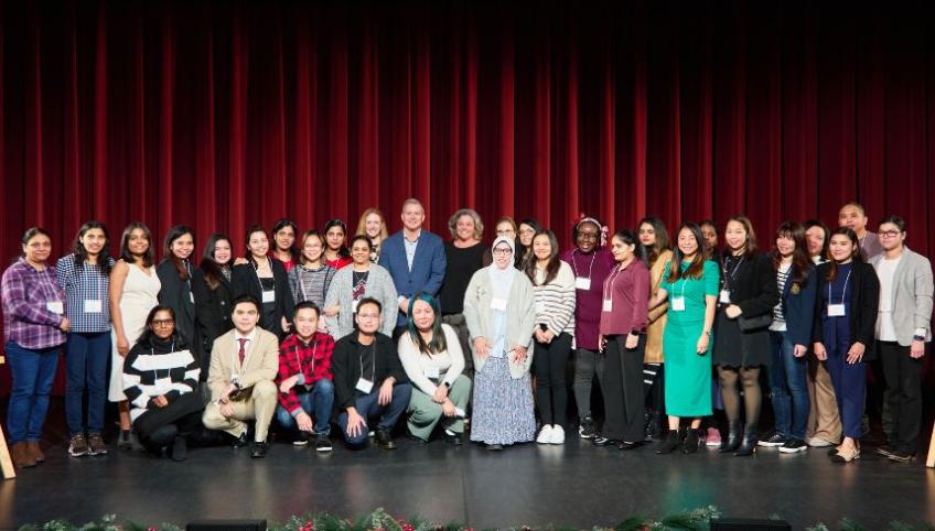 image of a group of people standing shoulder to shoulder on a stage with curtains in the background