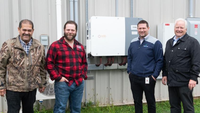 image of four people standing in front of some energy efficiency equipment outside a community rink