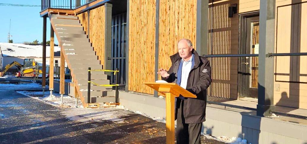 image of a person speaking at a podium outside a building