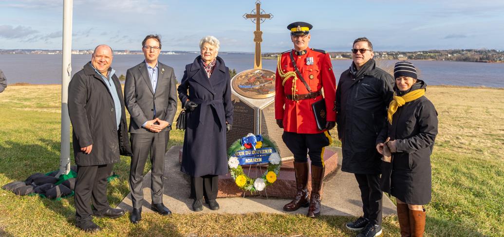 six people stand at the Acadian memorial at Skmaqn–Port-la-Joye–Fort Amherst National Historic Site 