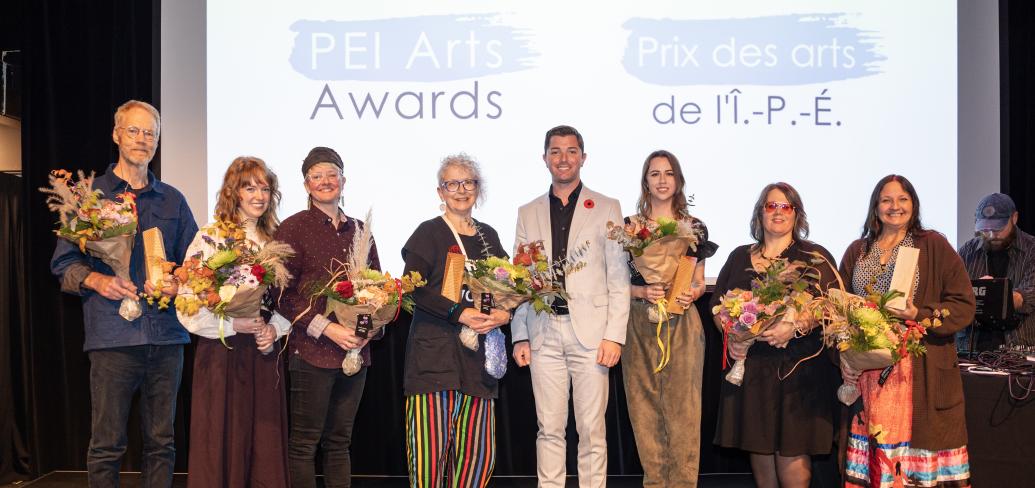 image of a line of people standing on a stage holding bouquets of flowers receiving awards