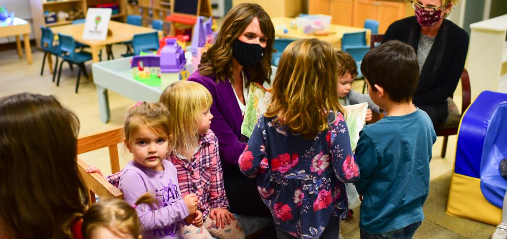 image of some adults and children sitting in a classroom reading area