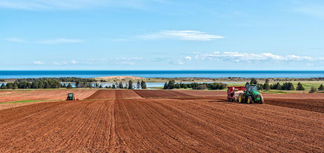 image of two farm tractors plowing a red soil field