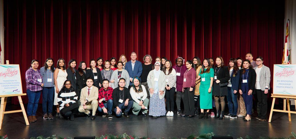 image of a group of people standing shoulder to shoulder on a stage with curtains in the background