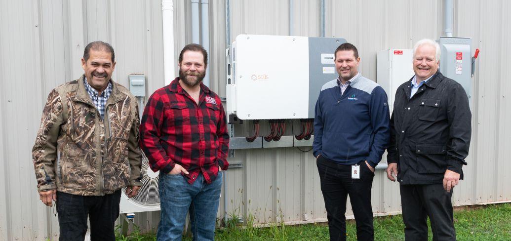 image of four people standing in front of some energy efficiency equipment outside a community rink