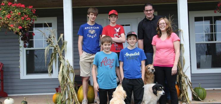 Family standing on front step of their home with two dogs