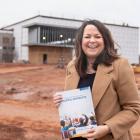 image of a person holding a document while standing in front of a building under contruction