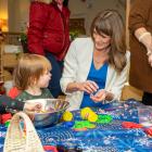 image of  some women sitting at a small table with some young children doing crafts