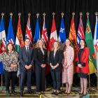 image of six people standing shoulder to shoulder in front of Canada's provincial flags