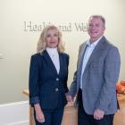 image of two people standing side by side in front of a desk in an office foyer