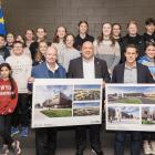 image of a group of students with three adults in front of them holding design renditions of a school