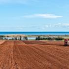 image of two farm tractors plowing a red soil field