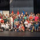 roupe de jeunes étudiants et de quelques adultes sur une scène de spectacle avec des drapeaux en arrière-plan