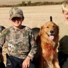 image of two youths with their dogs in a field of geese