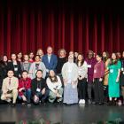 image of a group of people standing shoulder to shoulder on a stage with curtains in the background