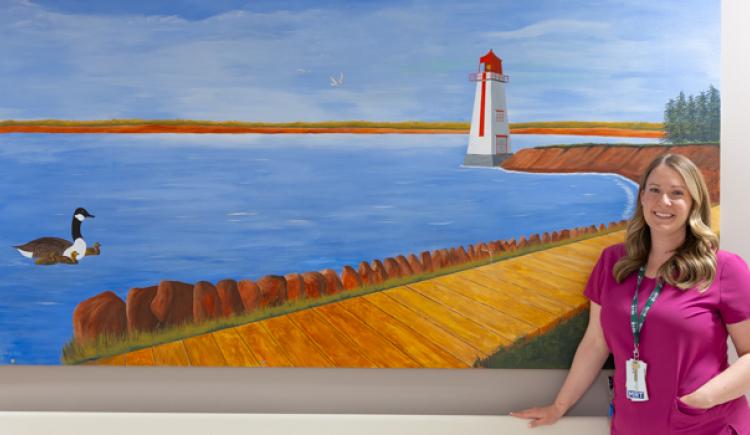 Kristy Peters, MRT, stands in front of mural at PEI Cancer Treatment Centre